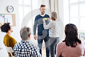 Counselor putting an adhesive note with the word sad on client during group therapy.