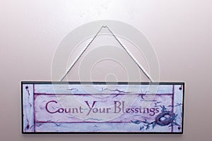 Count your blessings sign hangs on the wall in a home to remember thankfulness and remembering blessings in life photo