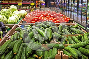 counter with fresh cucumbers, tomatoes, cabbage. Grocery store.