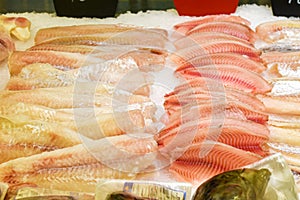 Counter with fresh fish in store. Fish fillet on ice. Chilled seafood, raw cod and sea bass fillets on ice at fish market.
