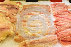 Counter with fresh fish in store. Fish fillet on ice. Chilled seafood, raw cod and sea bass fillets on ice at fish market.