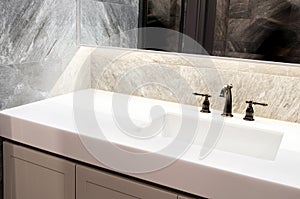 Counter top white marble,quartz with washbasin.Wall and floor beige,grey marble stone tile interior design of restroom or toilet b