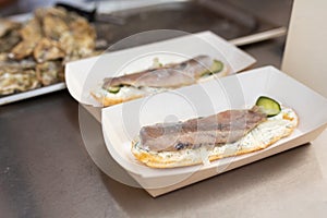 The counter on which lies a fish sandwich in an eco-friendly paper plate. Food and cooking equipment at a street food festival