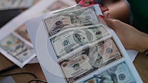 Counterfeiter cuts dollar bills with scissors closeup photo