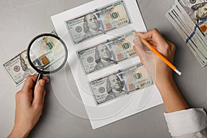 Counterfeiter drawing dollar banknotes with pencil at grey table, top view. Fake money concept