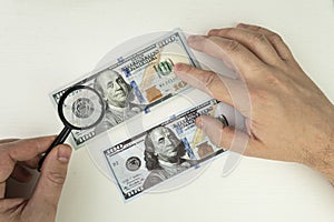 view money under a magnifying glass. Counterfeiter forges banknotes. Fake concept. Fake money American dollars, magnifier. photo