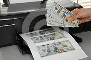 Counterfeiter printing dollar banknotes at grey table, closeup. Fake money concept