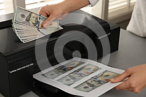 Counterfeiter printing dollar banknotes at grey table indoors, closeup. Fake money concept photo