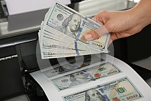 Counterfeiter printing dollar banknotes at table, closeup. Fake money concept