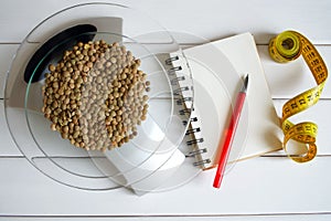 Counting calories, fat, carbohydrates and proteins in food. Lentil seeds on kitchen scales