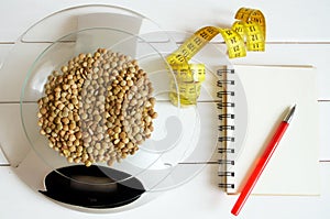 Counting calories, proteins, fats and carbohydrates in food. Lentil grains on table scales