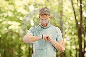 Counting calories. Wrist band gadget. Athlete check fitness tracker nature background. Athlete with bristle looks at