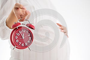 Counting hours expecting child birth. Motherhood concept. Pregnant woman holding alarm clock