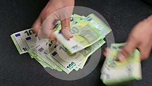 Counting a stack of 100 euro banknotes on a table