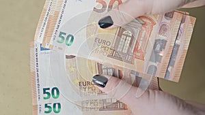 Counting Wealth: Woman's Hands with Black Nails Tallying 50 Euro Banknotes