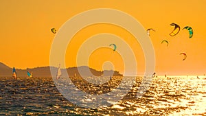 Countless kitesurfers and windsurfers are riding waves near Peljesac at sunset.