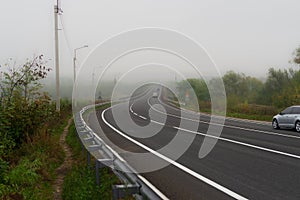 Country asphalt road in dense morning fog