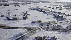 Country asphalt road with driving yellow bus in winter and small village from above. Shot. Aerial drone view in cold