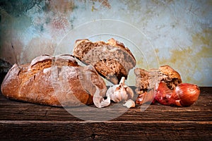 Country bread, garlic cloves and french dry shallots on a barn wood board