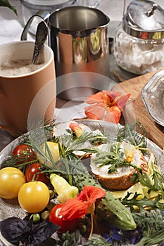 Country breakfast concept with bread, kitchen garden vegetables, herbs and edible flowers, coffee and milk