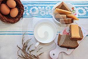 Country breakfast, milk and cereal bread, slices of cheese and fresh eggs in a basket