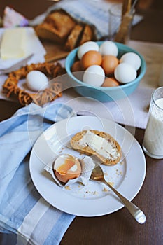 Country breakfast on rustic home kitchen with farm eggs, butter, wholegrain bread and milk.