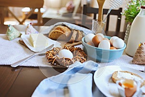 Country breakfast on rustic home kitchen with farm eggs, butter, wholegrain bread and milk.