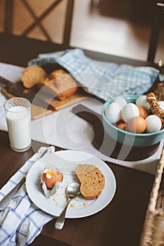 Country breakfast on rustic home kitchen with farm eggs, butter, wholegrain bread and milk.