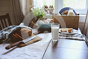 Country breakfast on rustic home kitchen with farm eggs, butter, wholegrain bread and milk.