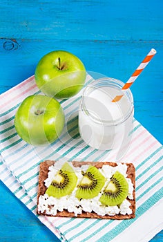 Country breakfast. Toast with cottage cheese and slices of kiwi, juicy green apples and home yogurt without sugar. Healthy eating.