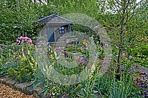 Country cottage and garden situated in a wooded rockery with a colourful display of flowers