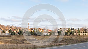 Country countryside landscape with beautiful two-story houses, evergreen trees along the fence, panoramic. Autumn rural landscape