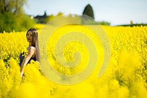 Country girl in a good mood walks in a rape field