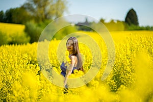 Country girl in a good mood walks in a rape field