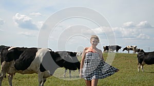 Country girl having fun on the background of a herd of cows in the meadow