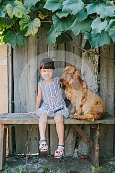 Country girl sitting on a bench with her dog under vine. wooden
