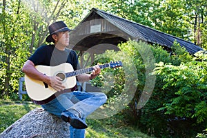 Country Guitar player at covered bridge