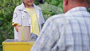 country holiday, adorable little boy helping his beekeeper grandfather paint beehives on beehive while relaxing in