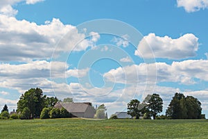 Country house with green grass in the foreground against a blue sky with white clouds in the background