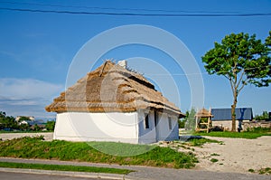 Country house under a thatched roof in the old style. Summer rural landscape. Vintage design