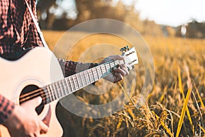 Country music, Man playing acoustic guitar in rice field