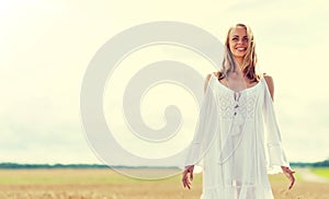 Smiling young woman in white dress on cereal field