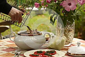Country outdoor still life with tureen with roasted meat, patisson, mashed potato on the table close up photo