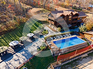 Country recreation center located in the woods with a large blue pool, sun loungers and tables. Photo from the drone.