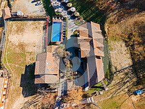 Country recreation center located in the woods with a large blue pool, sun loungers and tables. Photo from the drone.