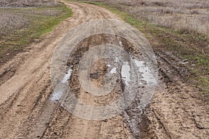 Country road. Autumn dirt road. Puddle and mud with deep ruts