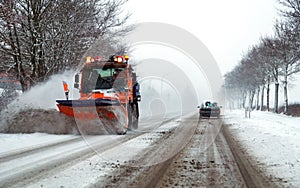 Country road in case of snowfall with evacuation vehicle in winter service