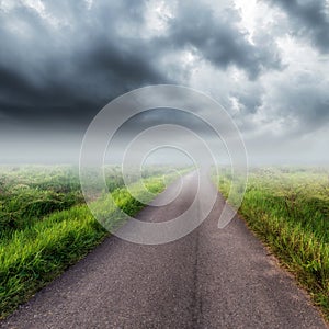 Country road on field and storm clouds