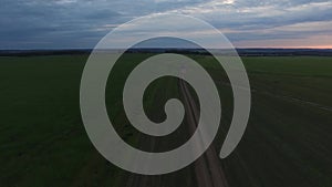 Country road through the fields, aerial view. Footage. Road through the summer countryside and beautiful clouds