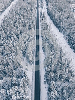 Country road going through the beautiful snow covered landscapes. Aerial view.